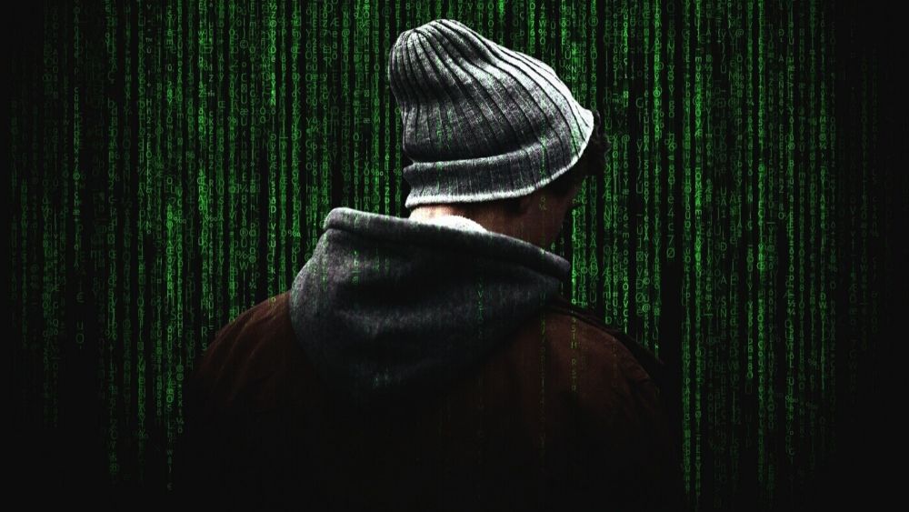 Man in Hoodie on Background of Green Computer Code