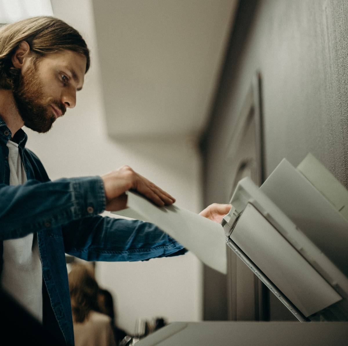 Business man putting documents into copier in an office setting.