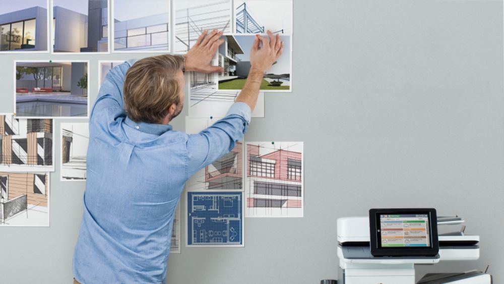 Man Pinning Printed Images to Office Wall