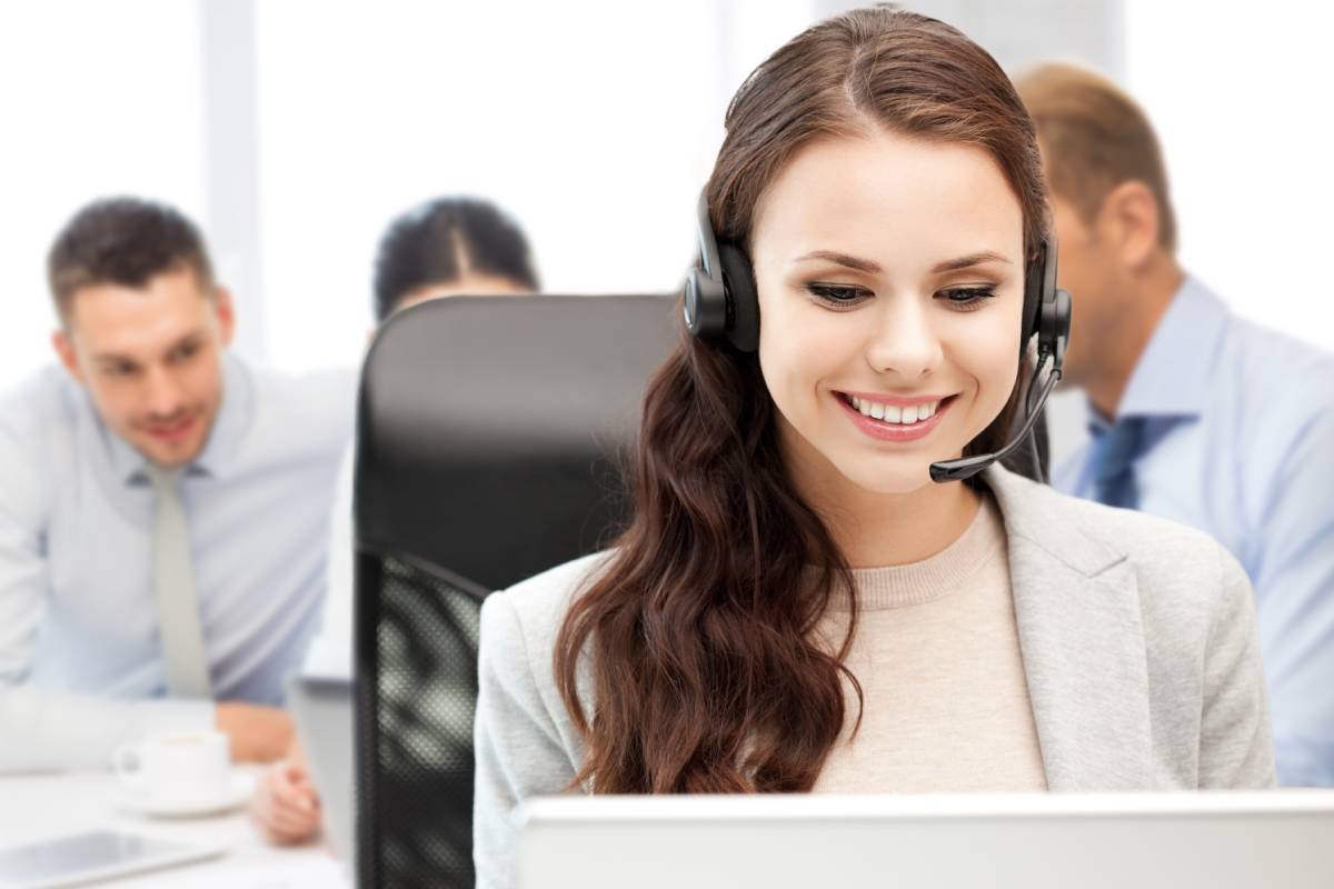 A female help desk employee smiling and wearing a headset